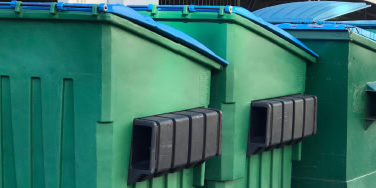 Row of green dumpsters with closed lids.