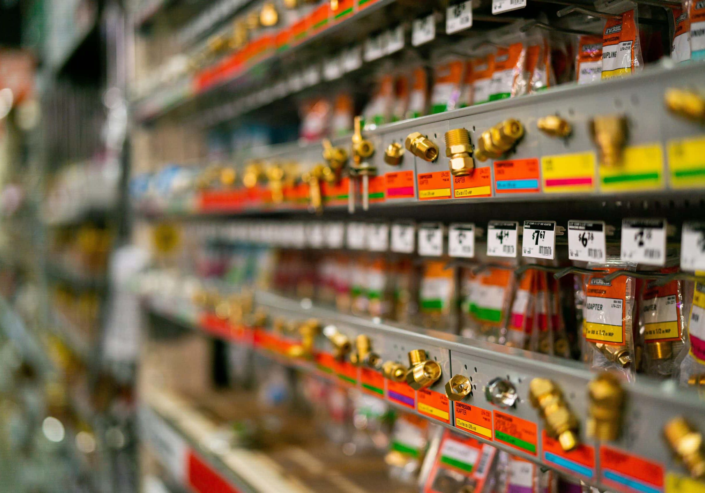 Hardware store aisle with brass fittings on shelves.